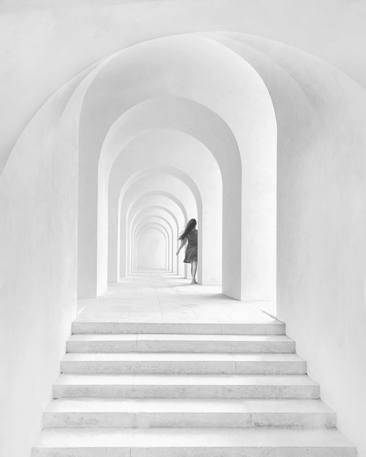 Woman in dress walking down a white hallway